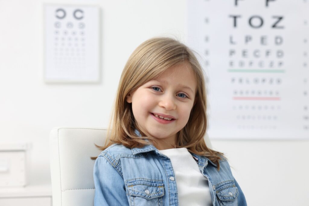 Young smiling girl sitting in the optometrists office.
